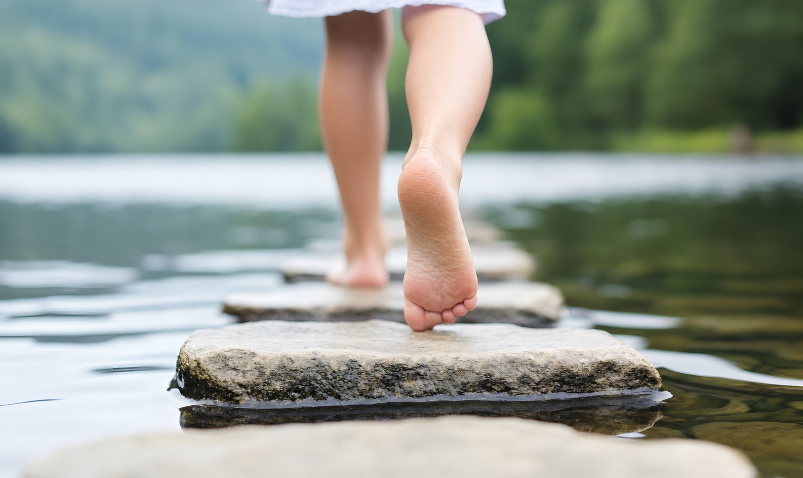 A child taking a careful step across stones in a stream